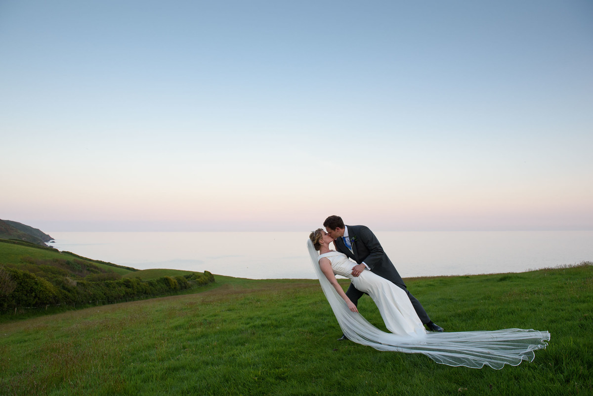 dramatic kiss between bride and groom on the Cornish coast with the sea behind