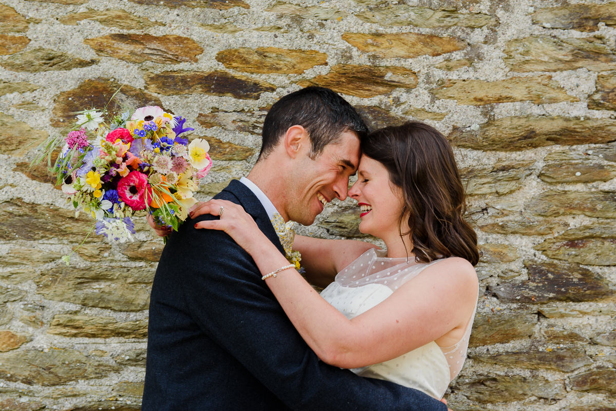 Bride and Groom laughing with colourful bouquet of flowers